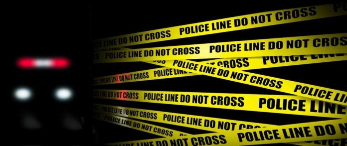 Yellow,Crime,Scene,Tape,Is,Seen,With,Police,Lights,And